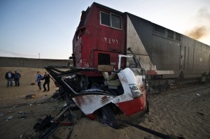 Egyptians walk past the site of an accident near a railway crossing, where a train ploughed into a truck and the mini-bus on November 18, 2013 in Dahshur, about 45 km south of Cairo. At least 26 people were killed and 28 other wounded, the health ministry said. The head of the Egyptian Railway Authority said the drivers of the vehicles had ignored warning lights and chains blocking entry to the crossing, and tried to go across the tracks. (AFP PHOTO / KHALED DESOUKI)