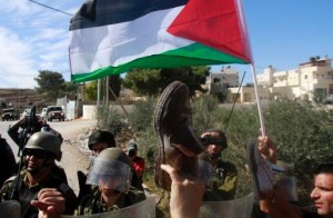 Palestinian protesters wave shoes in front of Israeli soldiers at a demonstration against the Israeli separation barrier and the expansion of Jewish settlements in the West Bank village of Maasarah, near Bethlehem, on October 25, 2013 (AFP, Musa al-Shaer)